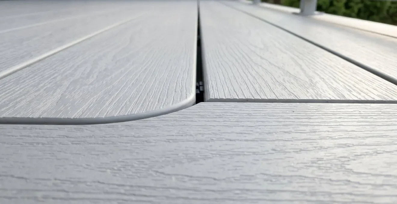 Gros plan détaillé montrant un raccord impeccable entre une section courbe et une section droite de lames de terrasse en PVC composite, avec transition fluide visible